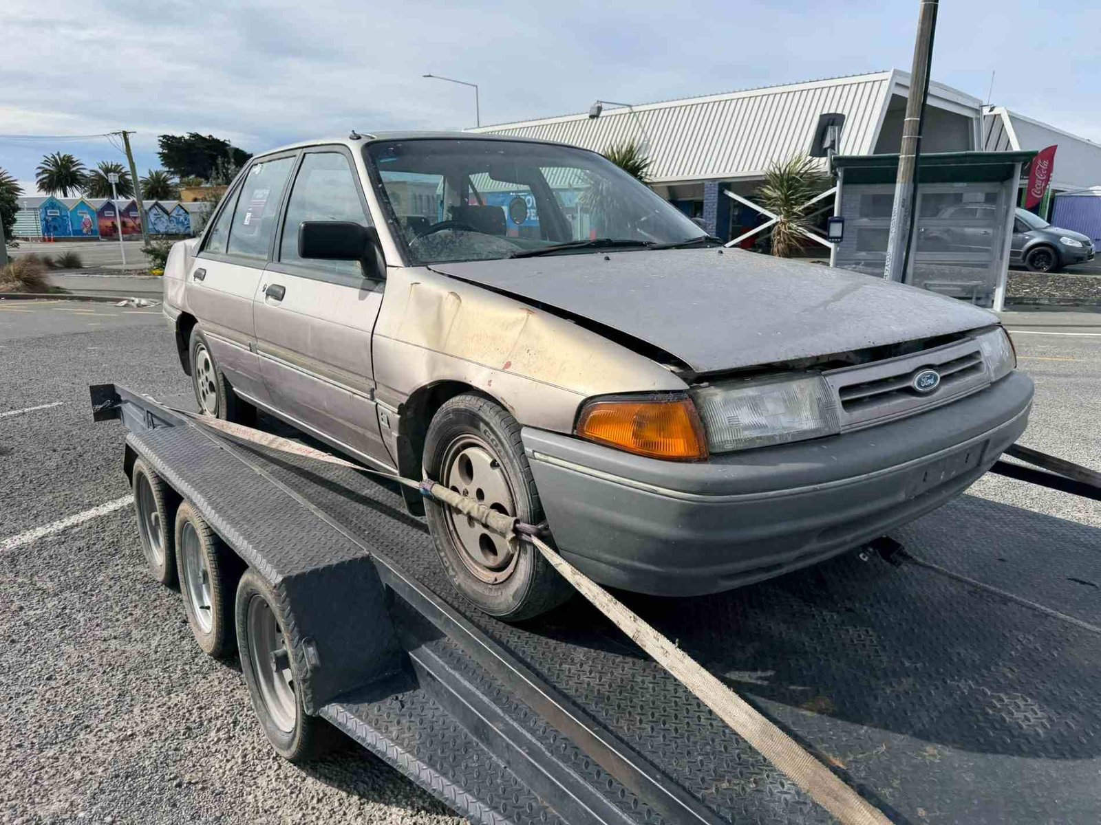 Well used Ford Laser sedan loaded on a trailer for removal in Christchurch by our cash for cars team