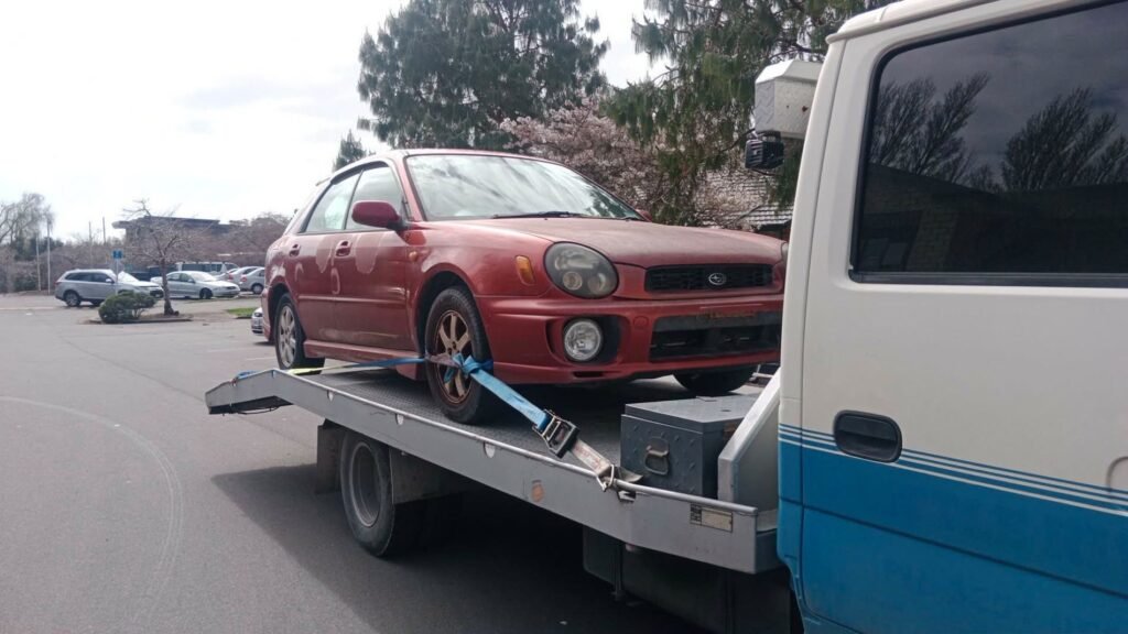 Red Subaru Impreza wagon strapped to the tow truck on a Christchurch street